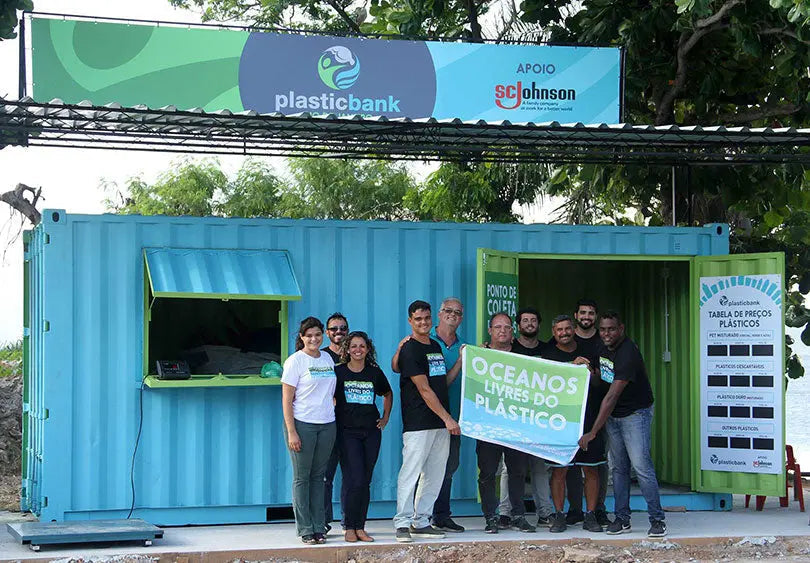 Photo d’un groupe engagé devant une station Plastic Bank, symbole d’actions locales pour un océan sans plastique.